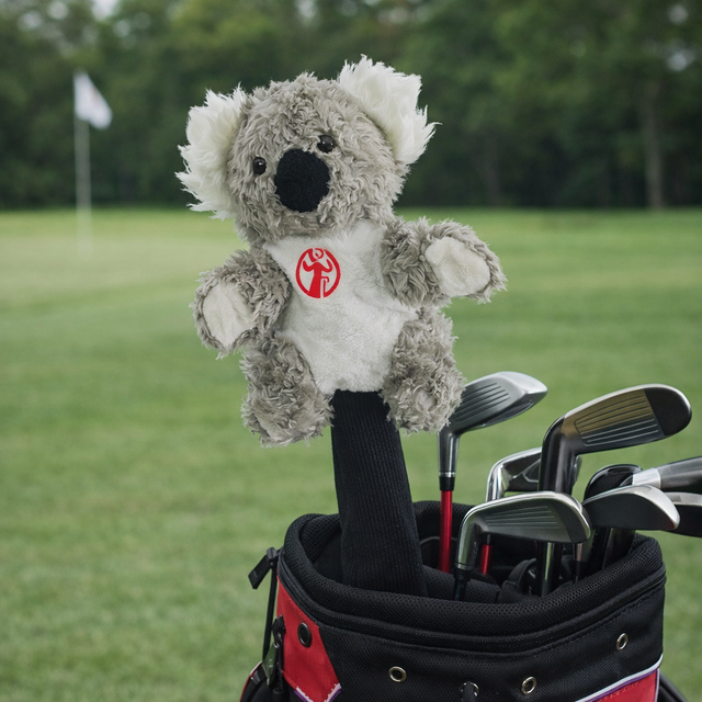 Plush koala toy with a red logo in a golf club bag on a golf course