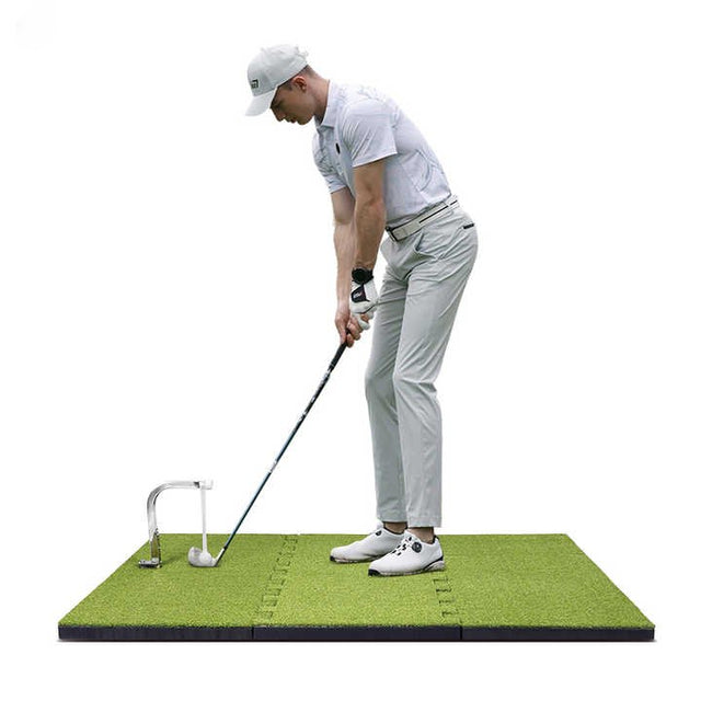 Person practicing golf on a green mat with a white background